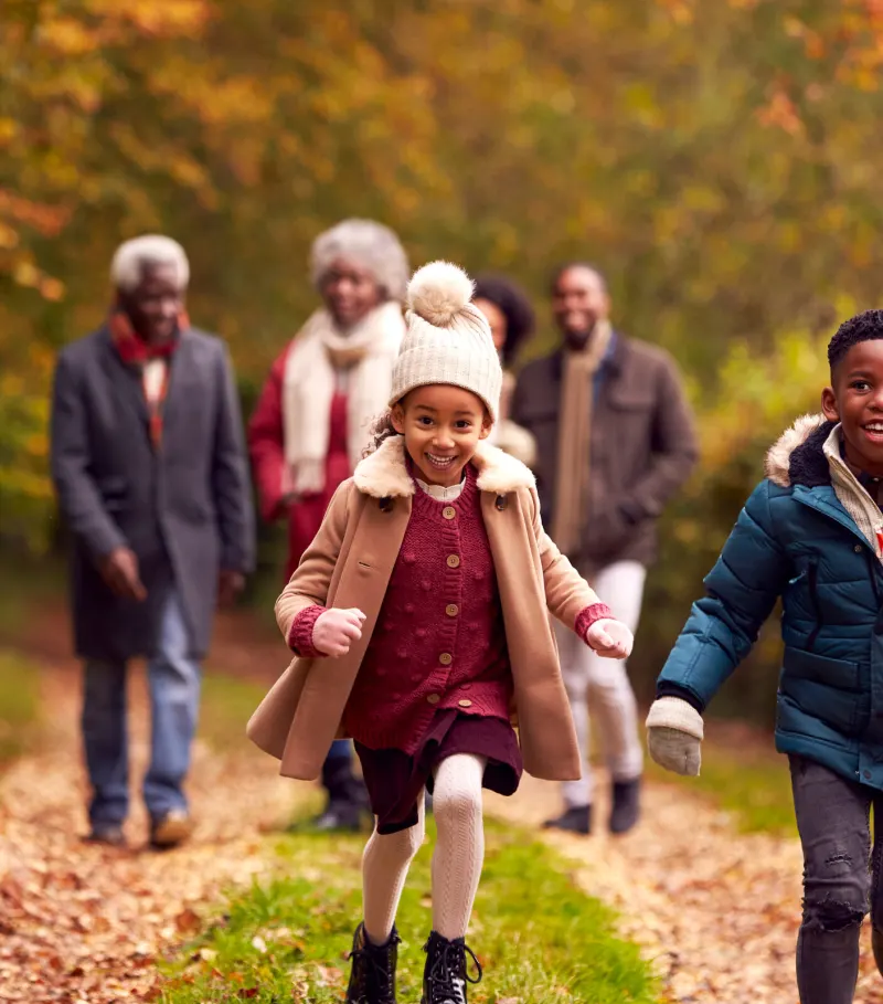 A family walking together along a woodland path in autumn