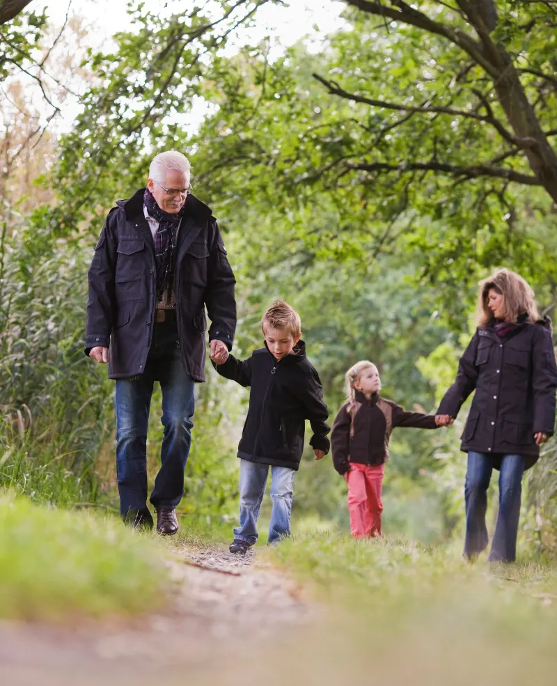 Grandparents walking along a country path, hand in hand with their grandchildren