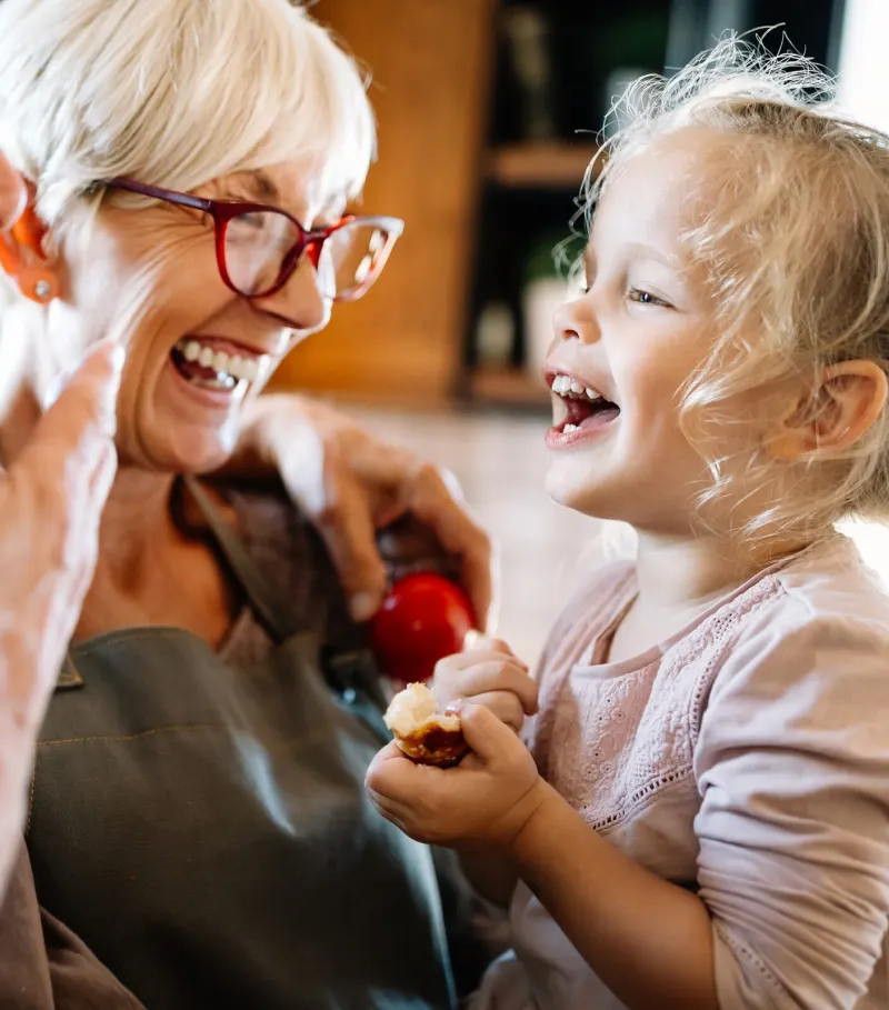 Grandparents laughing with their granddaughter in the kitchen